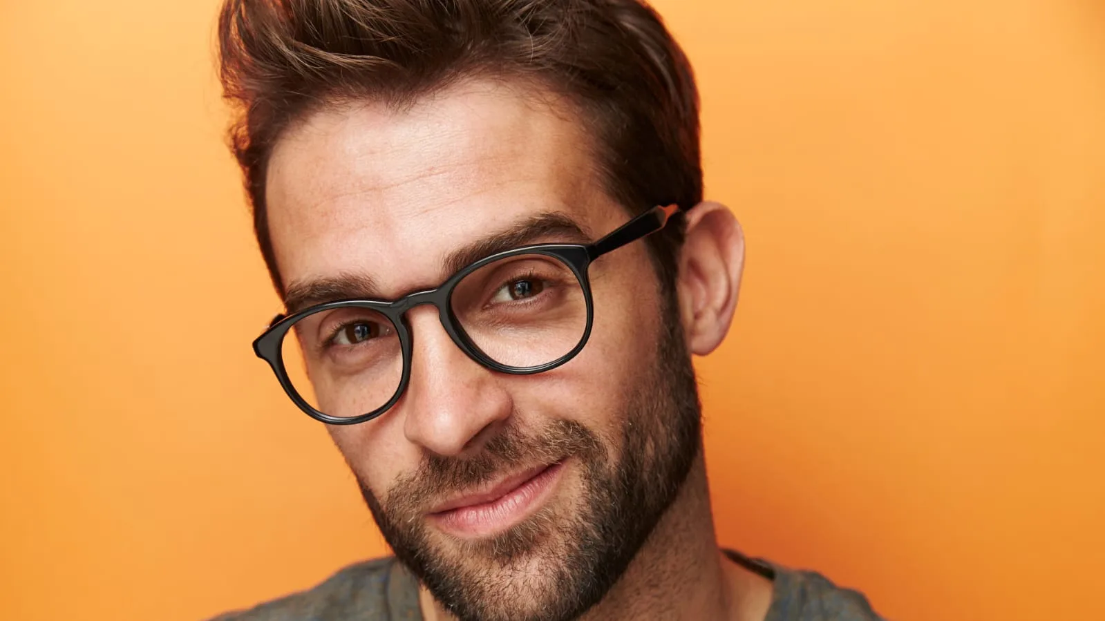 A smiling man with a beard wearing round black glasses